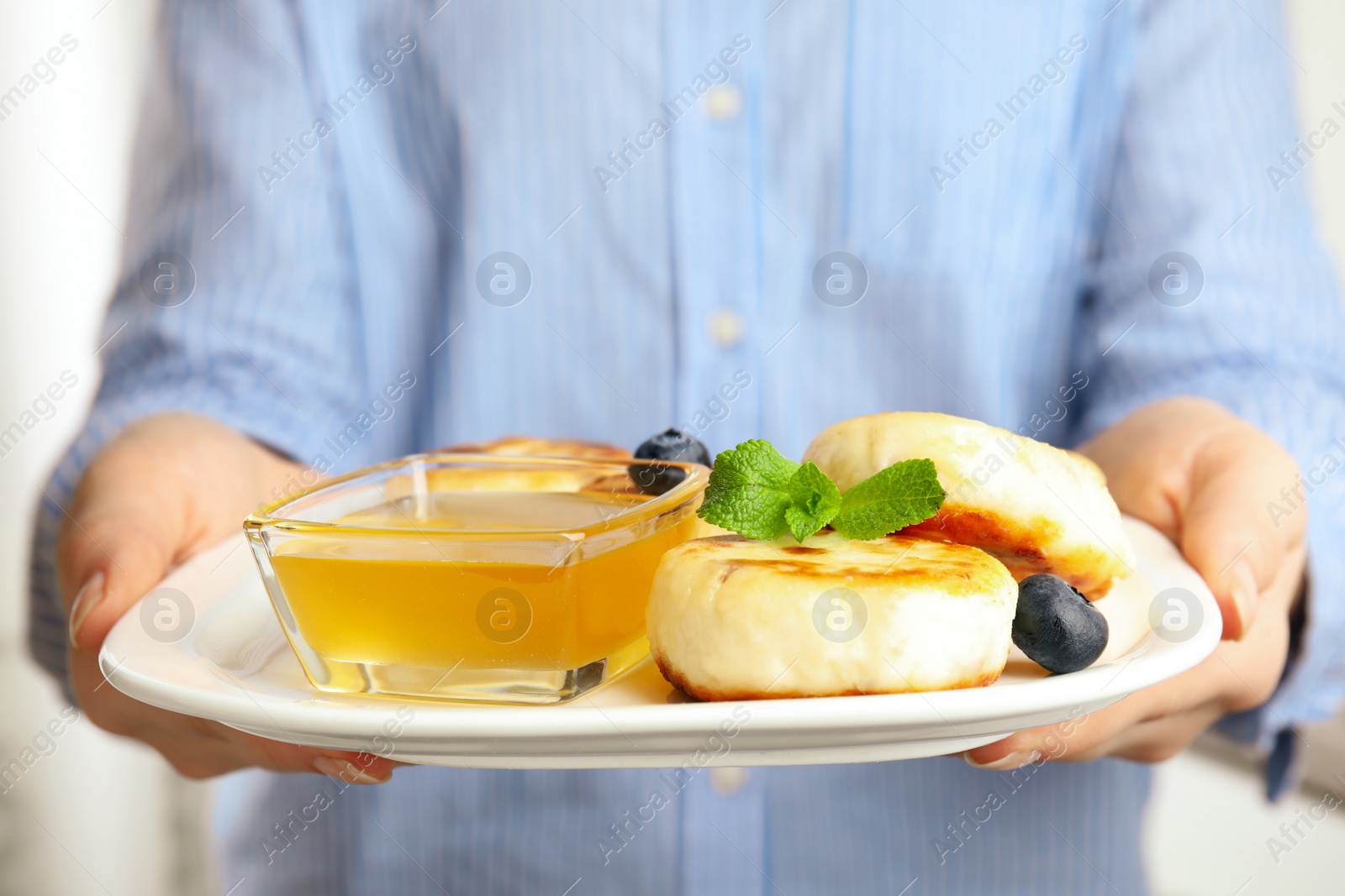 Photo of Woman with plate of delicious cottage cheese pancakes, closeup