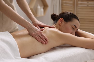 Photo of Woman receiving back massage on couch in spa salon