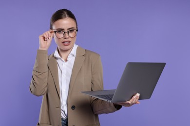 Photo of Beautiful woman in glasses with laptop on violet background