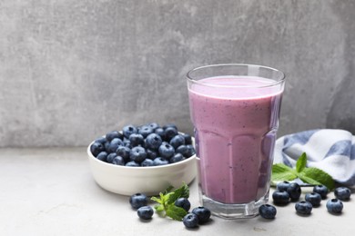 Photo of Glass of freshly made blueberry smoothie on light grey table. Space for text