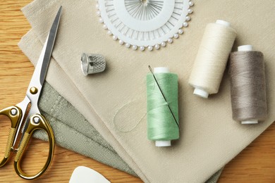 Photo of Flat lay composition with threads and sewing tools on wooden table