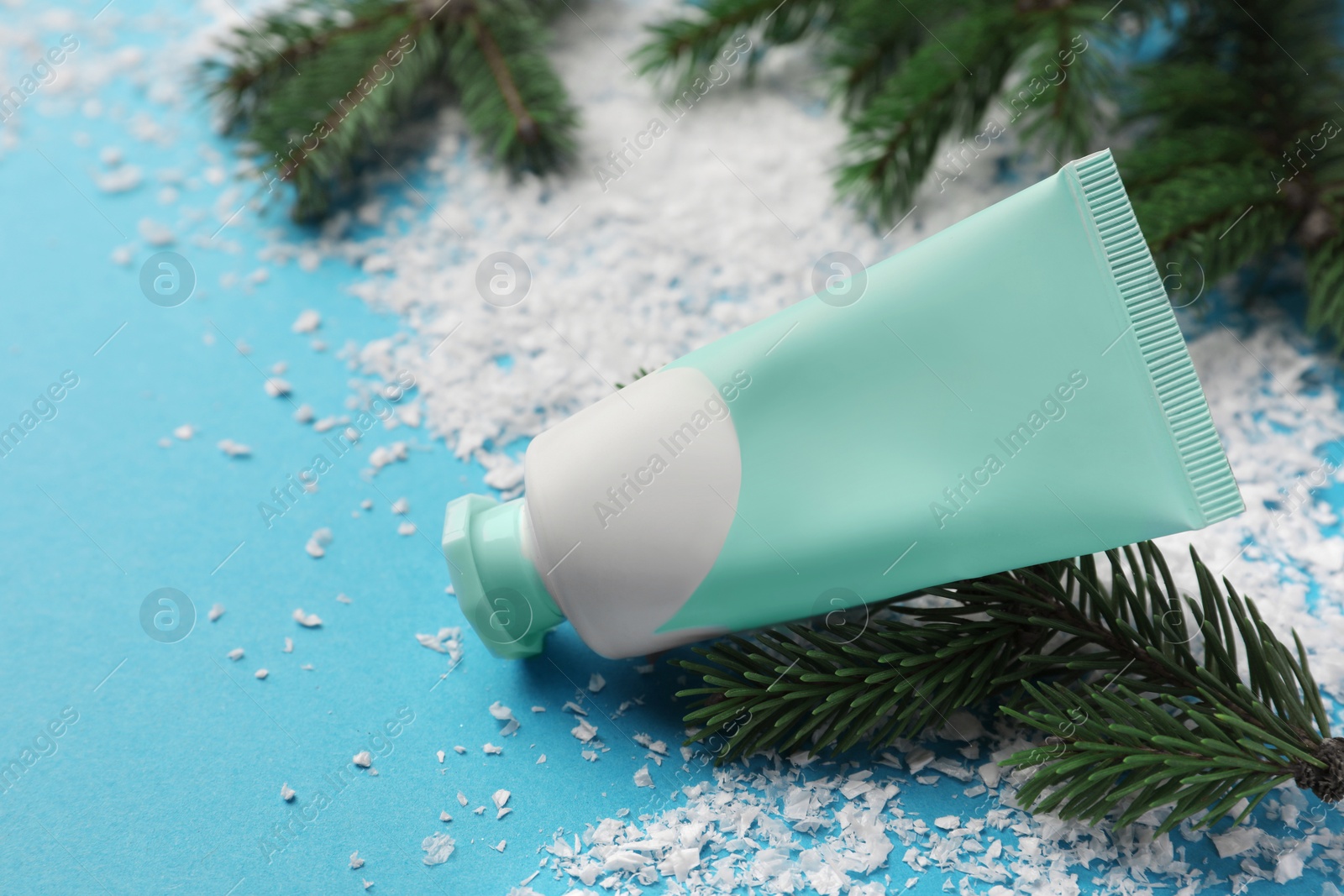 Photo of Tube of hand cream and Christmas decor on light blue background, space for text. Winter skin care