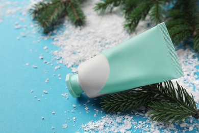 Photo of Tube of hand cream and Christmas decor on light blue background, space for text. Winter skin care