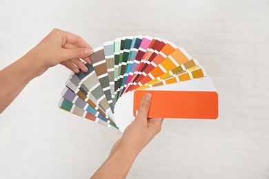 Photo of Female interior designer with color palette samples on light background, closeup