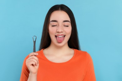 Photo of Happy woman with tongue cleaner on light blue background