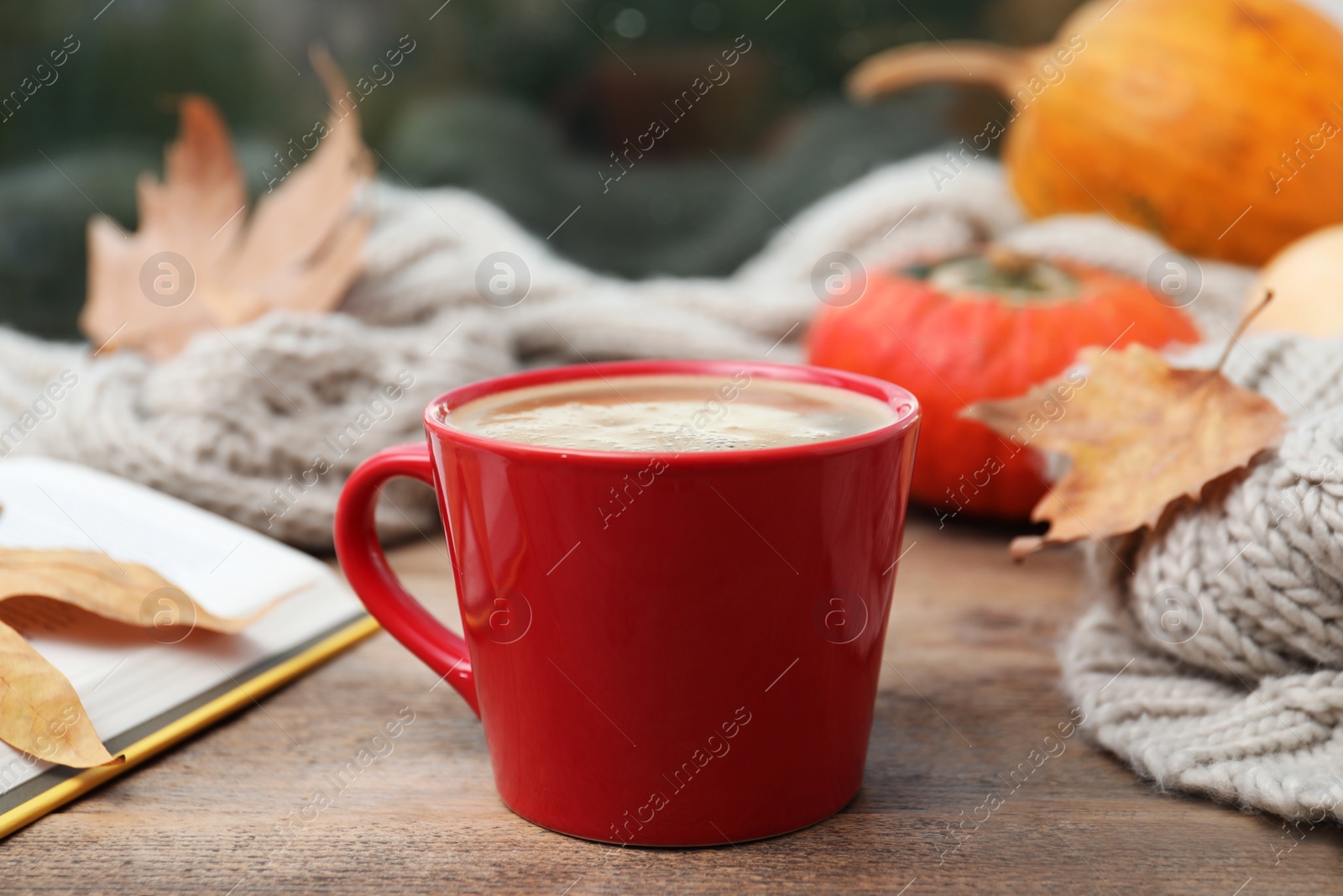 Photo of Cup of hot drink and scarf on window sill indoors. Cozy autumn atmosphere