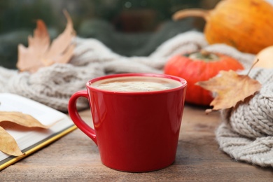Cup of hot drink and scarf on window sill indoors. Cozy autumn atmosphere
