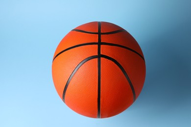 Photo of One orange basketball ball on light blue background, top view