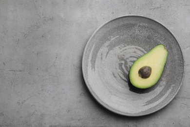 Photo of Half of delicious ripe avocado on grey table, top view. Space for text