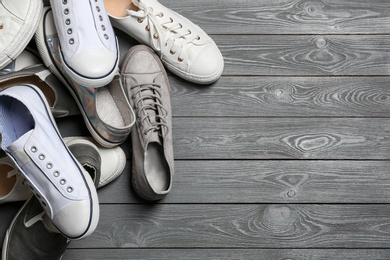 Photo of Pile of shoes and space for text on wooden background, top view
