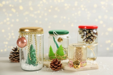 Photo of Handmade snow globes and fir cones on light table