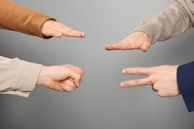 Photo of People playing rock, paper and scissors on grey background, closeup