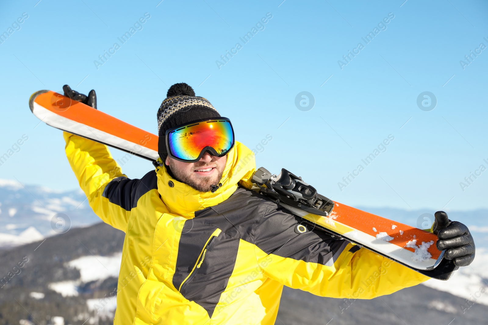 Photo of Happy man with ski equipment in mountains. Winter vacation