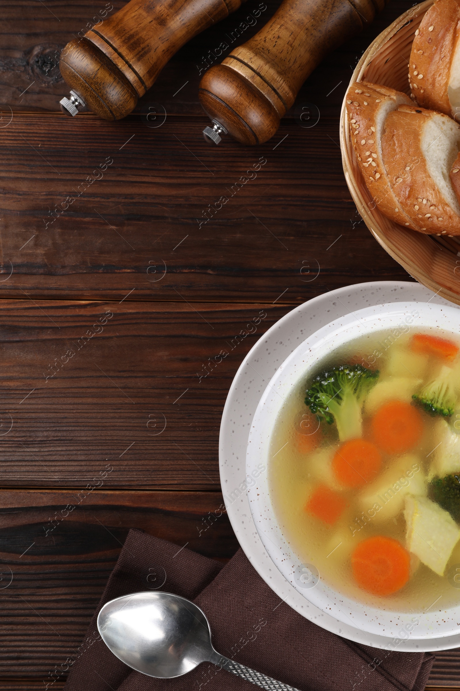 Photo of Tasty chicken soup with vegetables in bowl served on wooden table, flat lay. Space for text
