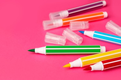 Many bright markers on pink background, closeup