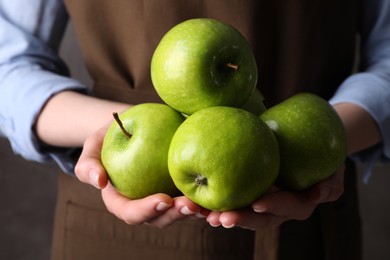 Photo of Woman holding ripe green apples, closeup view