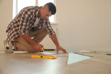 Professional worker installing new parquet flooring indoors