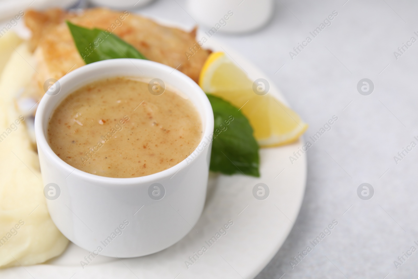 Photo of Delicious turkey gravy served on light grey table, closeup. Space for text