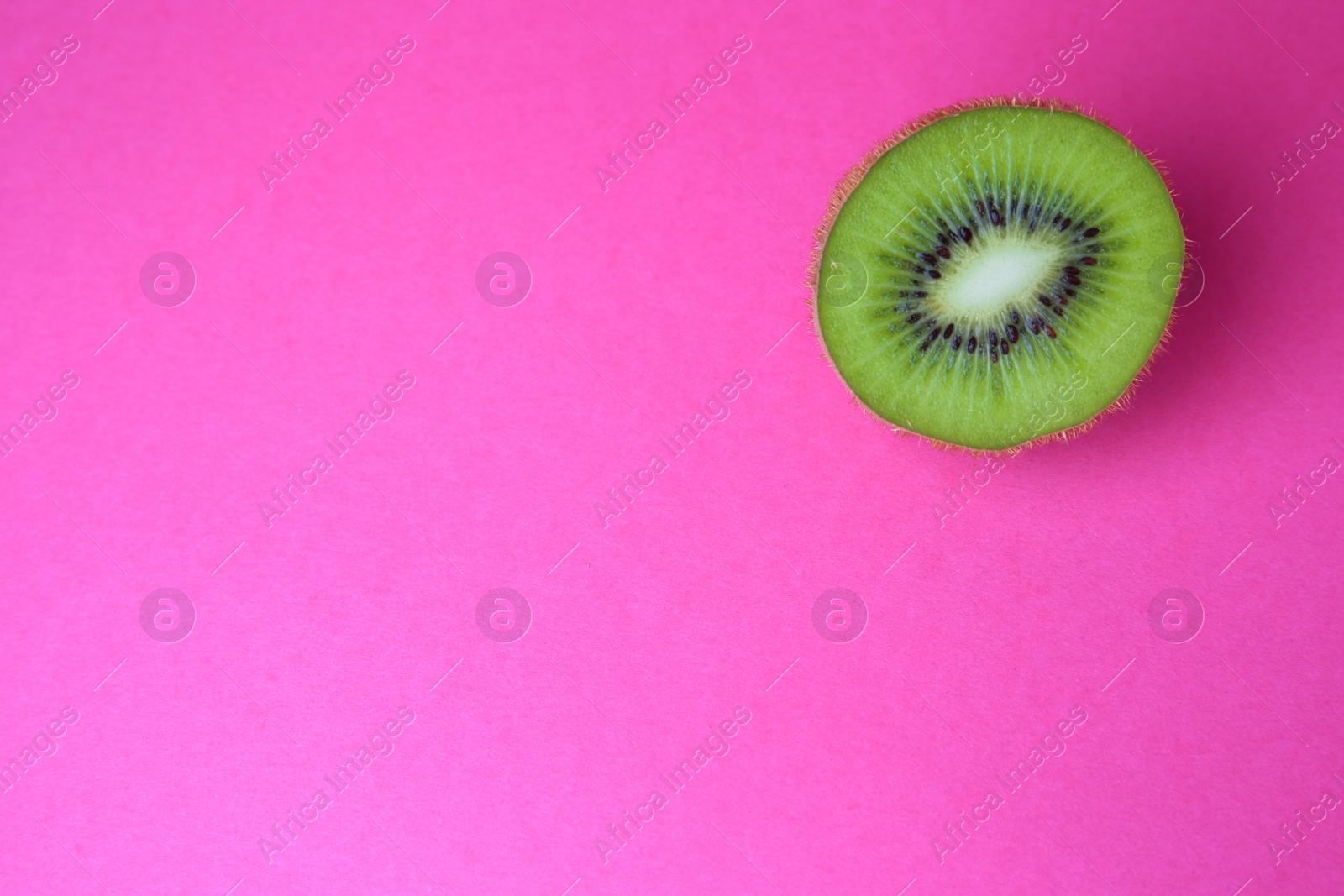 Photo of Cut fresh ripe kiwi on pink background, top view. Space for text