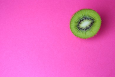 Photo of Cut fresh ripe kiwi on pink background, top view. Space for text