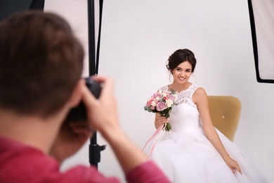 Photo of Professional photographer taking photo of beautiful bride in studio