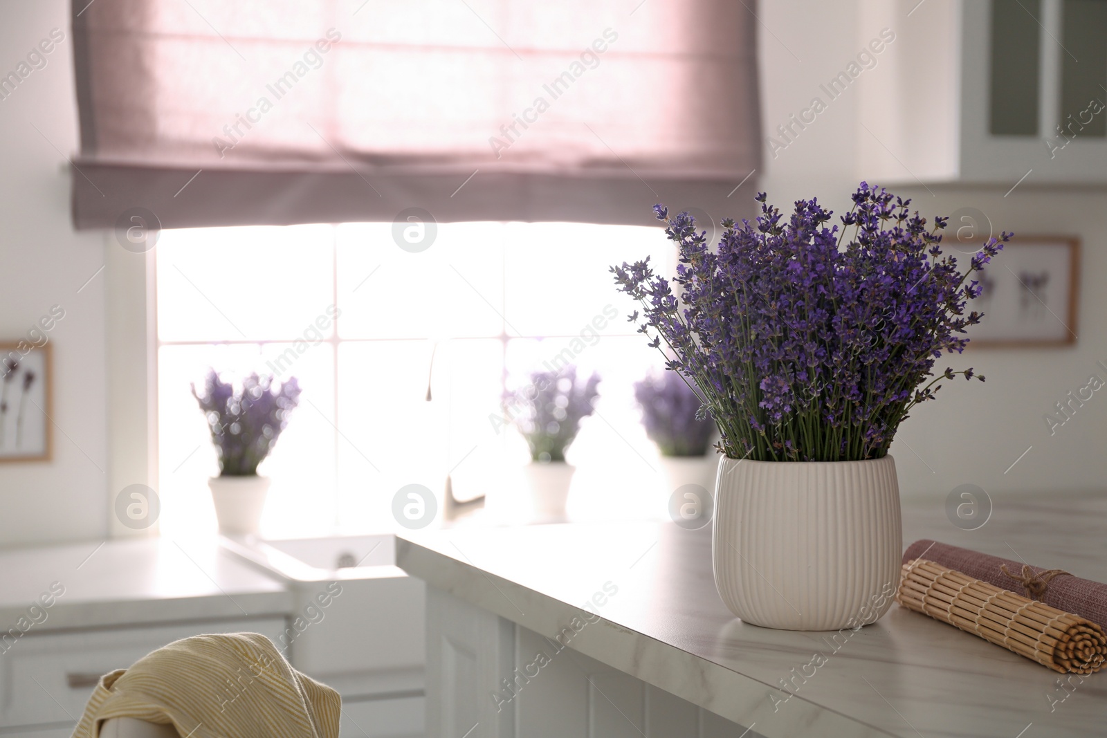 Photo of Beautiful lavender flowers on white table in kitchen. Space for text