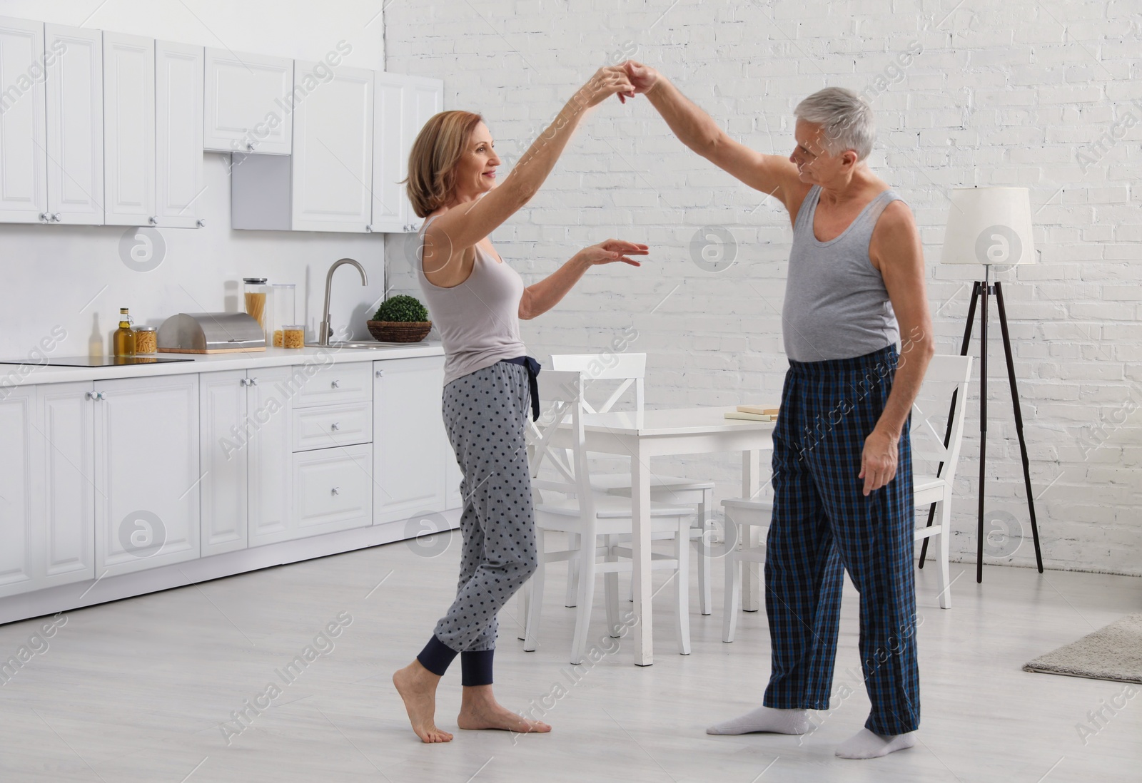 Photo of Happy senior couple dancing together in kitchen