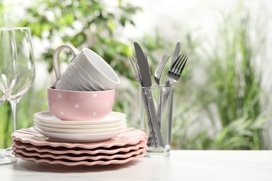 Photo of Beautiful ceramic dishware, glasses, cutlery and cup on white table outdoors, space for text
