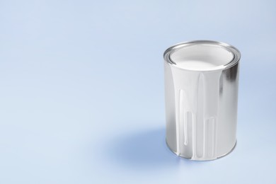 Photo of Can of white paint on light blue background, space for text