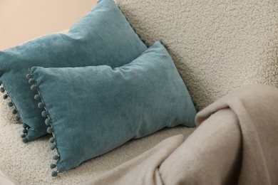 Photo of Soft blue pillows and blanket on armchair