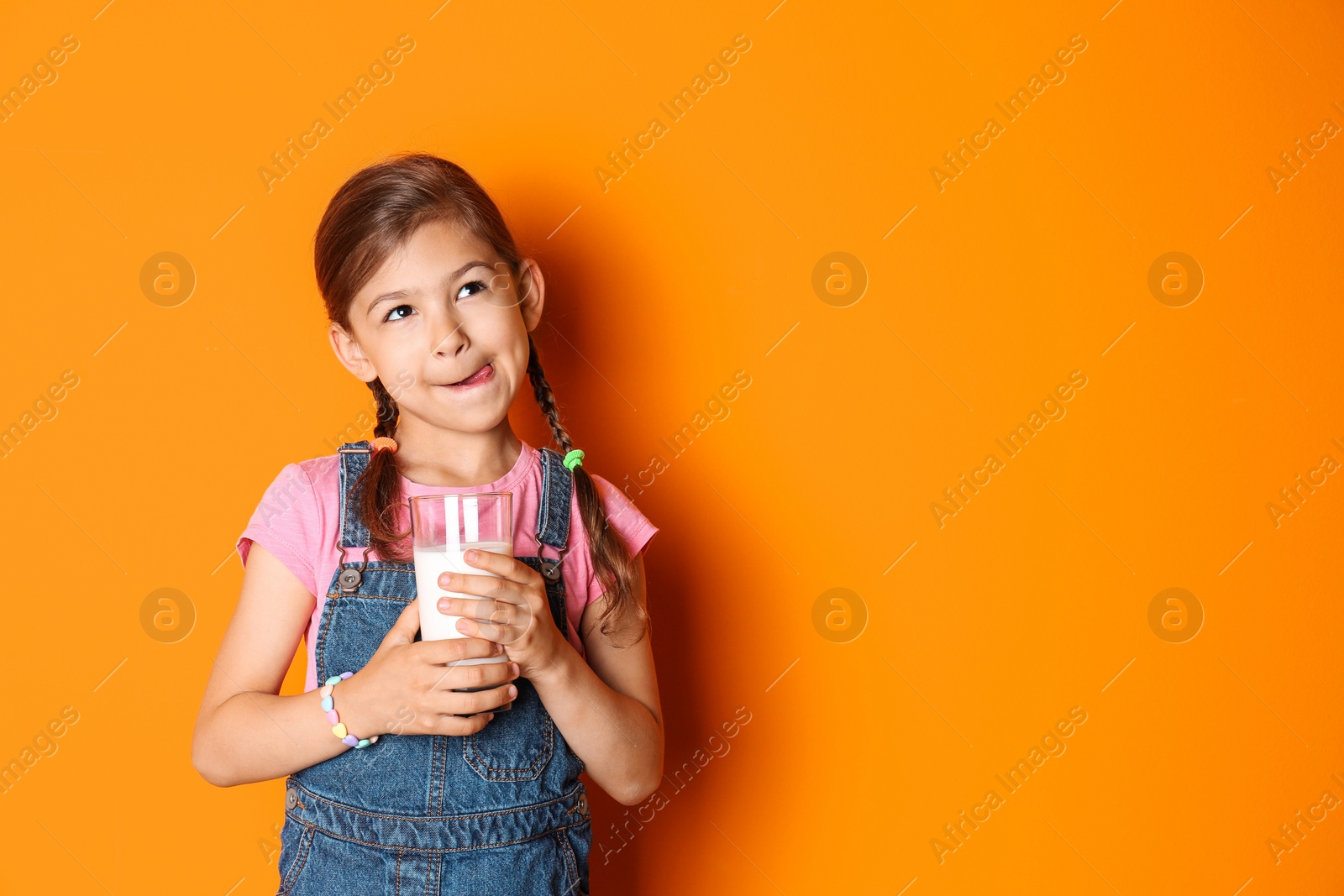 Photo of Cute little girl with glass of milk on color background