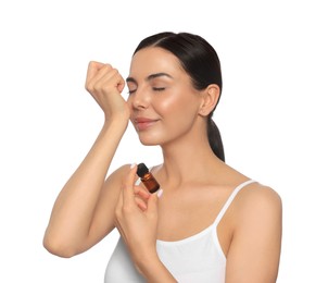 Photo of Young woman smelling essential oil on wrist against white background