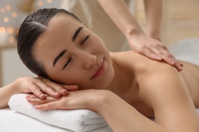 Photo of Woman receiving back massage on couch in spa salon