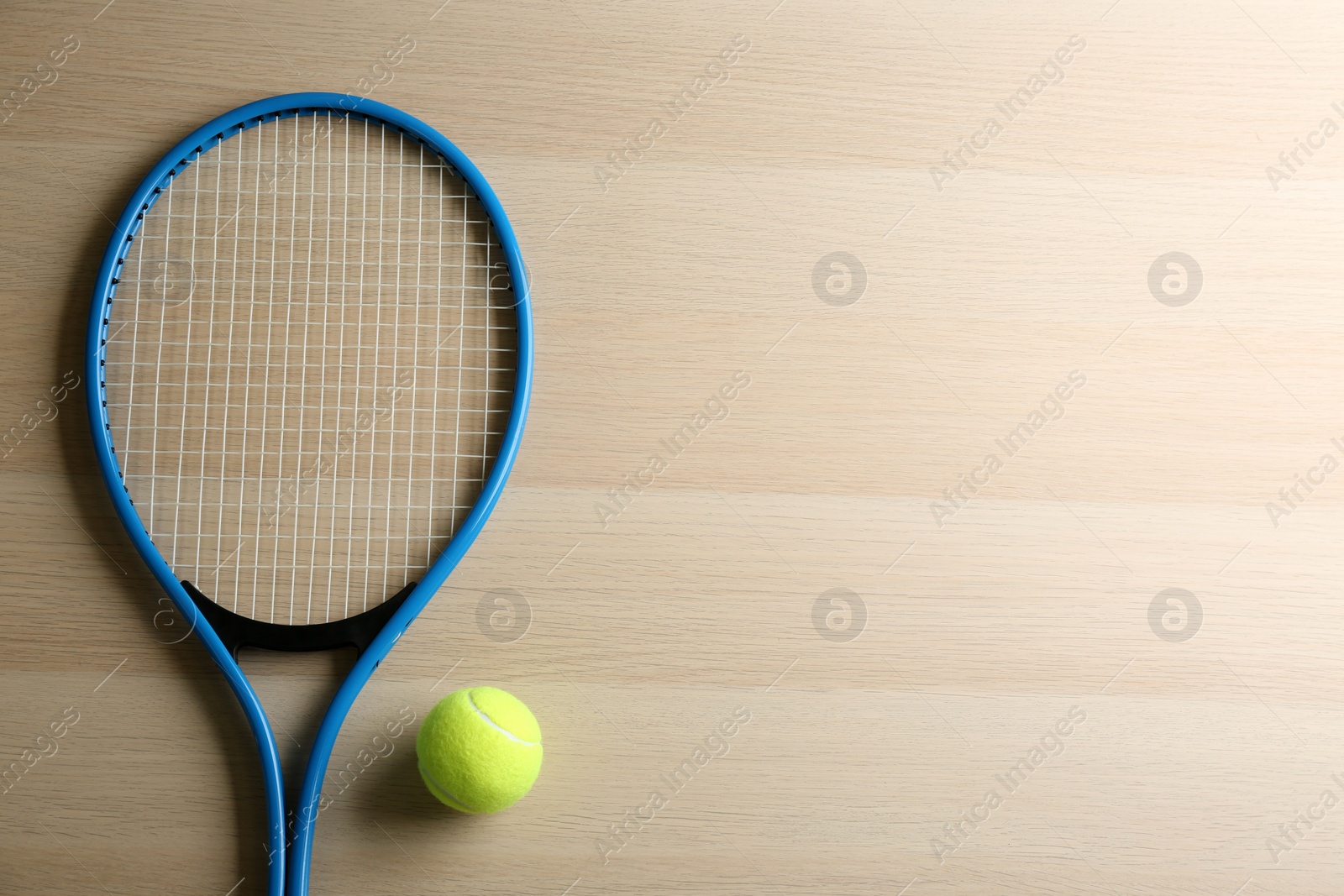 Photo of Tennis racket and ball on wooden table, flat lay. Space for text