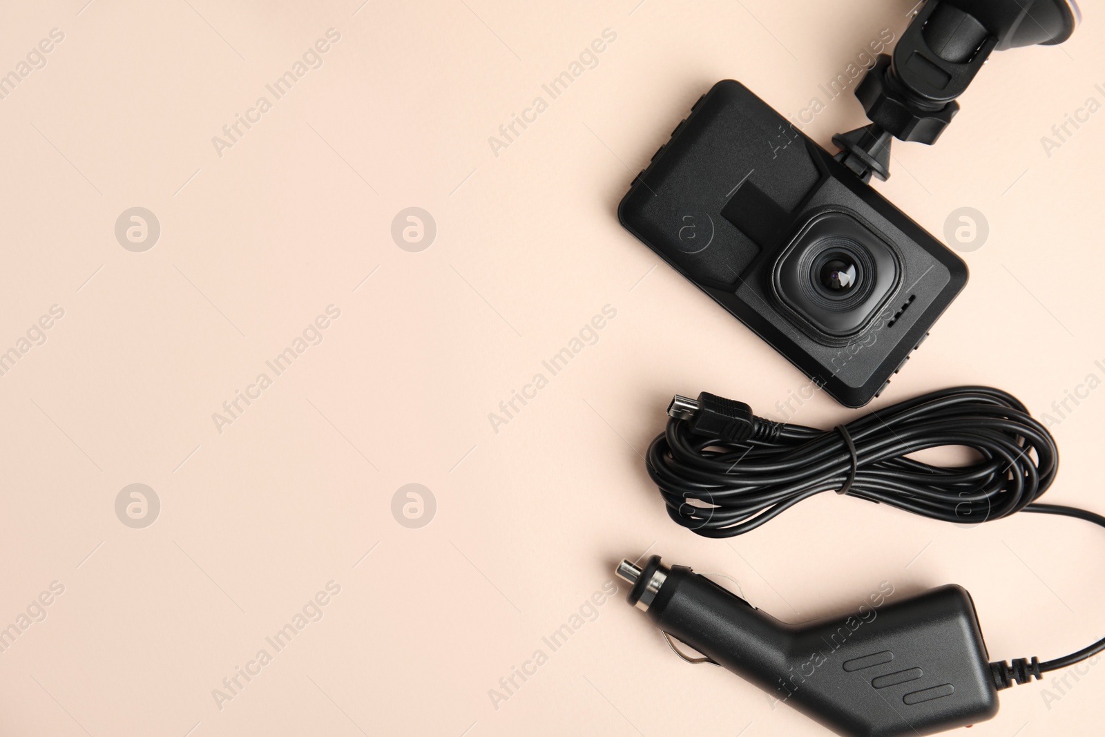 Photo of Modern car dashboard camera, suction mount and charger on light pink background, flat lay. Space for text