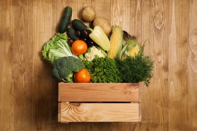Photo of Different fresh ripe vegetables and crate on wooden table, top view