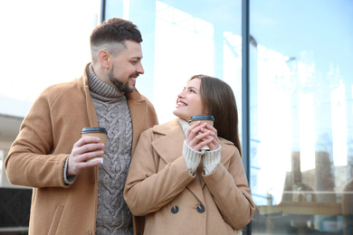 Photo of Lovely couple with cups of coffee on city street in morning