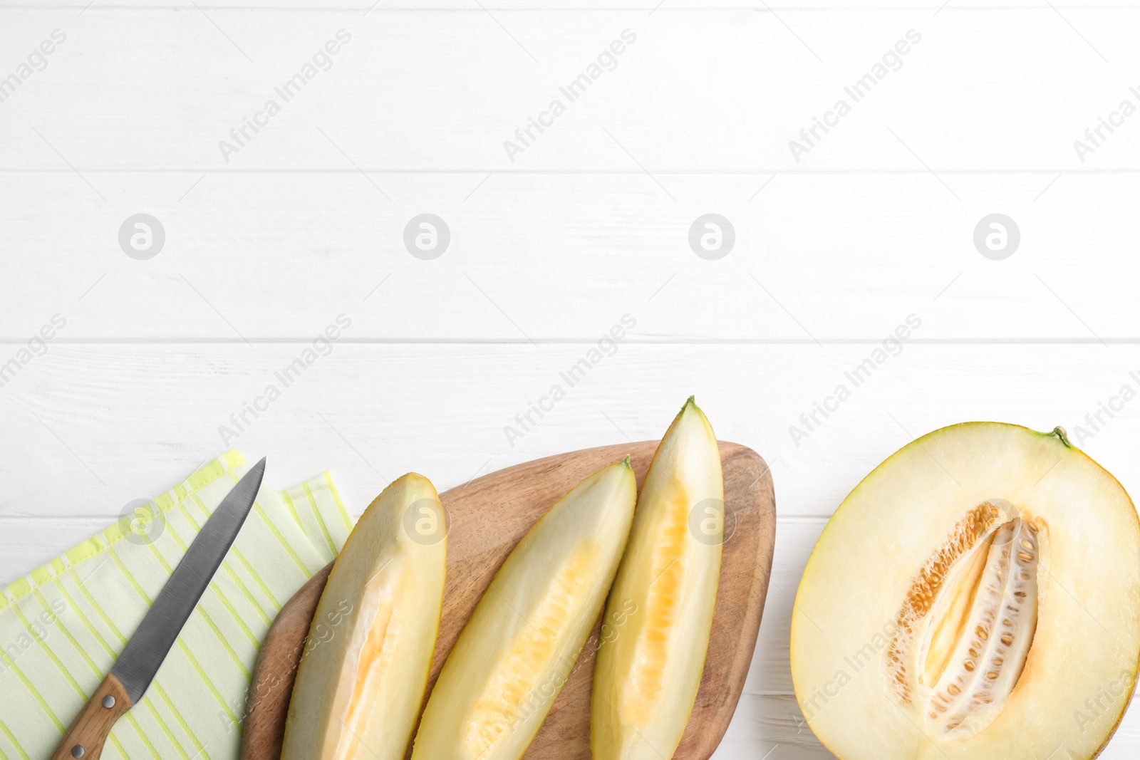 Photo of Pieces of delicious honeydew melon on white wooden table, flat lay. Space for text