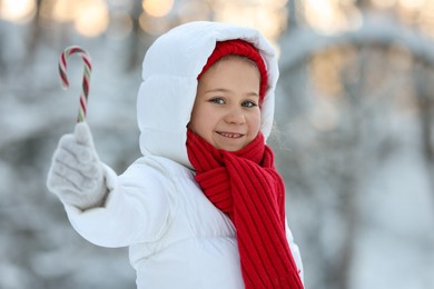 Cute little girl with candy cane in winter park