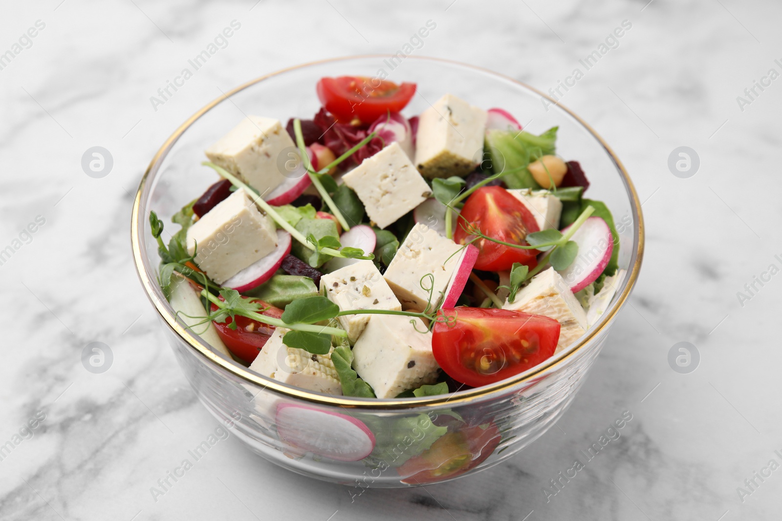 Photo of Bowl of tasty salad with tofu and vegetables on white marble table, closeup