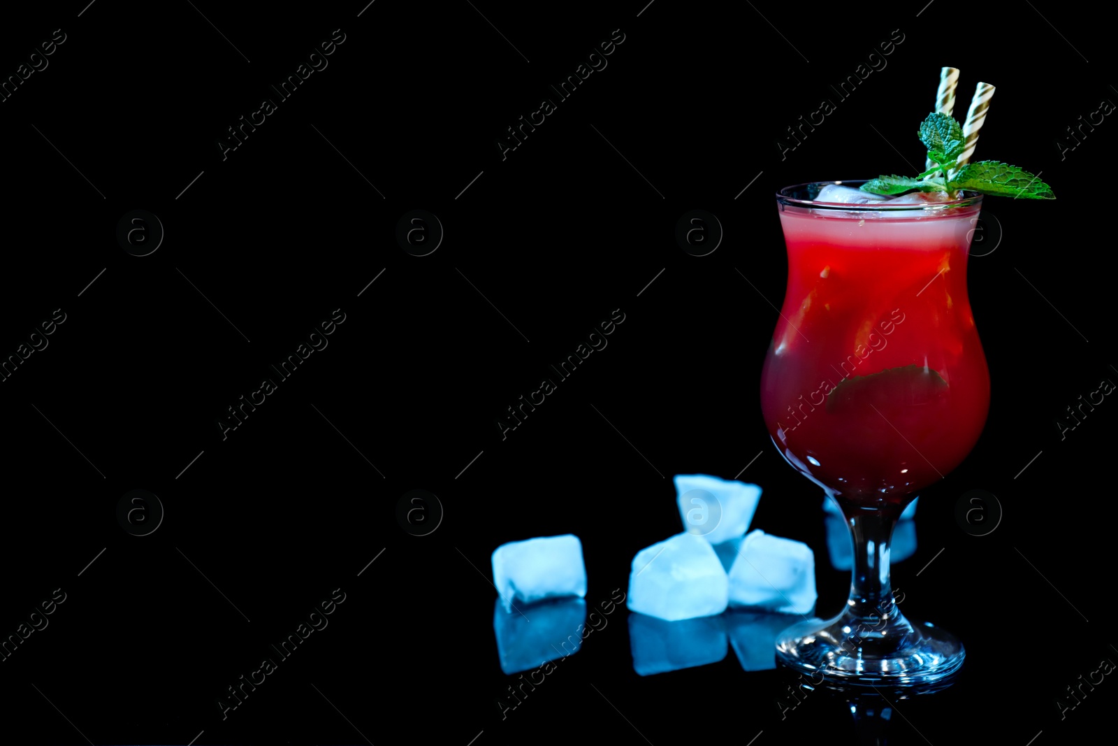 Photo of Glass of delicious cocktail and ice on black background. Space for text