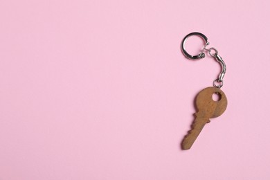 Photo of Wooden keychain in shape of key on pale pink background, top view. Space for text