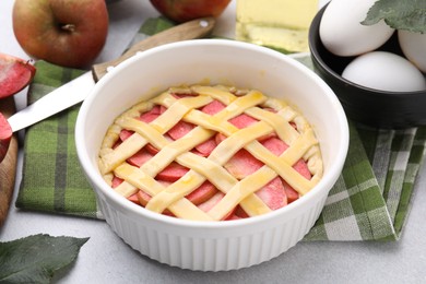 Photo of Raw apple pie and ingredients on light grey textured table, closeup