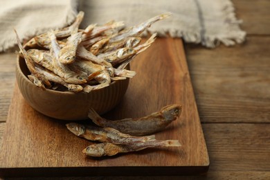 Photo of Delicious dried anchovies on wooden table, closeup. Space for text