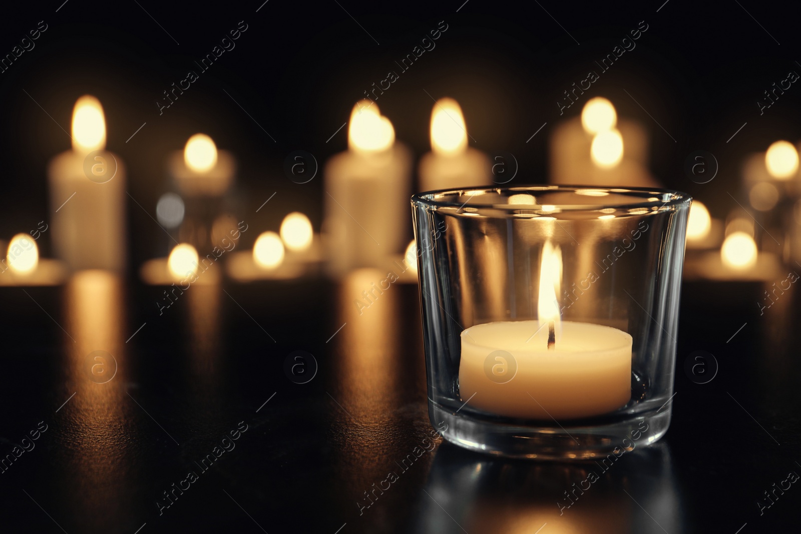 Photo of Burning candle on table in darkness, space for text. Funeral symbol