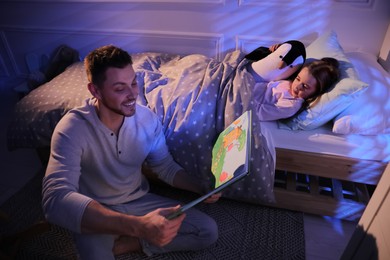 Father reading bedtime story to his daughter at home