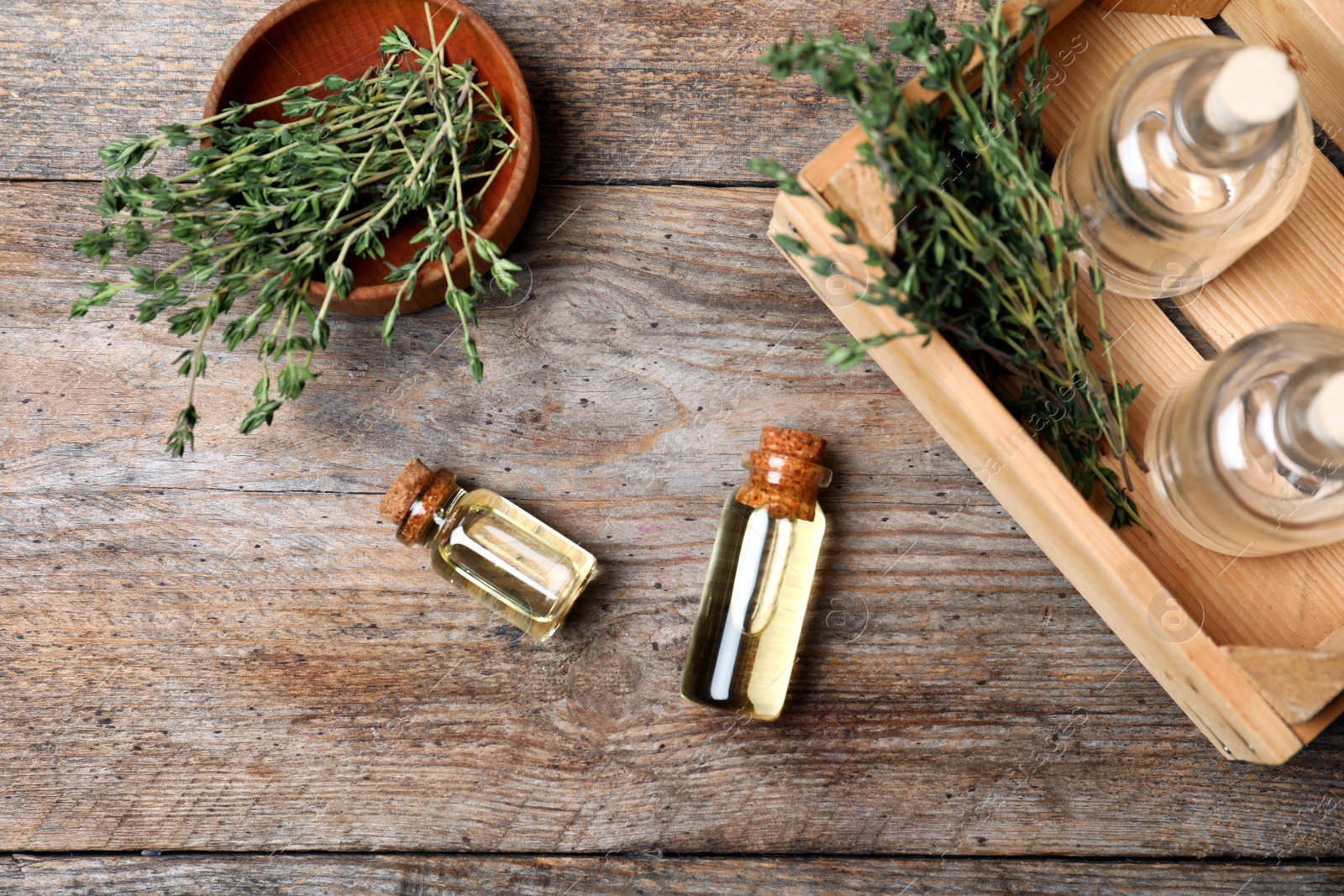Photo of Flat lay composition with essential oil in glass bottles and thyme on wooden background