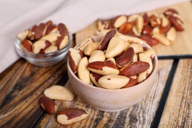 Photo of Bowls with delicious Brazil nuts on wooden table