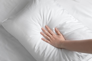 Young woman touching soft white pillow, closeup