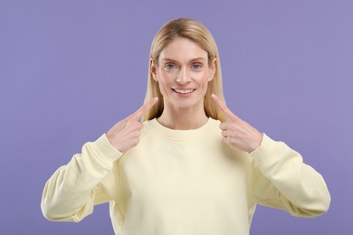 Woman showing her clean teeth and smiling on violet background